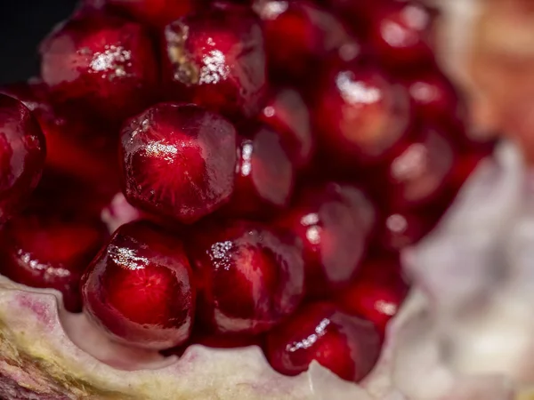 slice the pomegranate with red grains on a black background, a narrow focus area