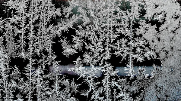 Frosty natural pattern on a winter window, texture of frosty patterns, dendritic image structure