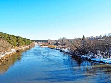 Köprüden nehre kadar olan bölgede akşamları şehrin dışında güneş parlar, karlar erir, çam ormanı, kırsal bölge, Güney Urallar 'ın Kashtak köyü yakınlarındaki Miass Nehri.