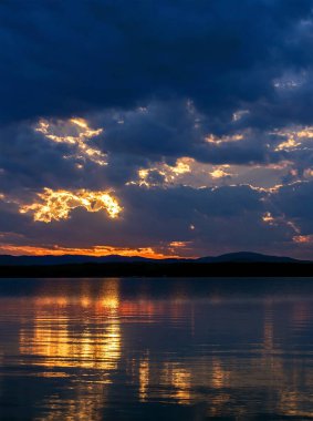 Gölün üzerinde karanlık akşam gökyüzü, dramatik bulutlar, güneşin ışığı hala görünür, suda yansımalar, yaz akşamı, Güney Uviller, Uvildy Gölü