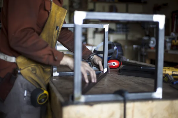 Meubels op maat ambachtsman assembleert kruk ondersteunende structuur. — Stockfoto