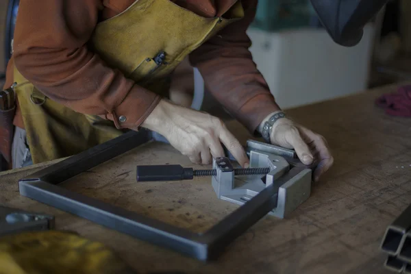 Woodworker ajuste le cadre métallique pour le siège de tabouret . — Photo