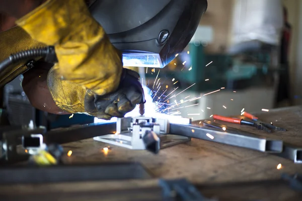 Welder adding finishing touches to steel support frame for furniture. — Stock Photo, Image