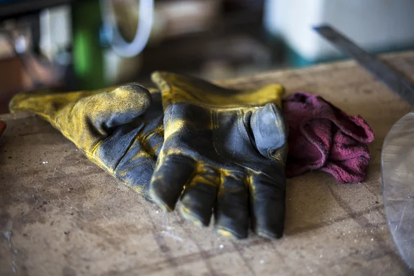 Pošpiněná svářecí rukavice umístěte na stůl jako dělník přestávky na oběd. — Stock fotografie