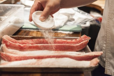 Tuz ve baharat balık bir suşi şefi ekler. 