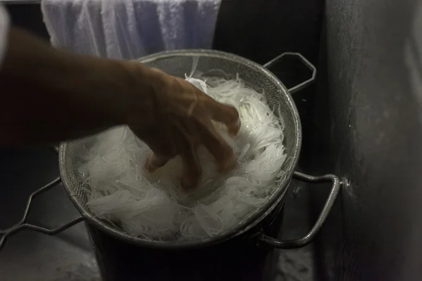 Een chef-kok koelt hete noedels in ijsbad. — Stockfoto