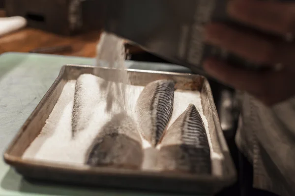Een sushi chef-kok wordt toegevoegd zout en kruiden om te vissen. — Stockfoto