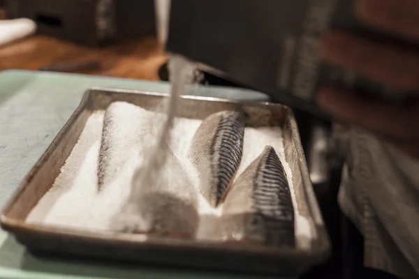 Een sushi chef-kok wordt toegevoegd zout en kruiden om te vissen. — Stockfoto
