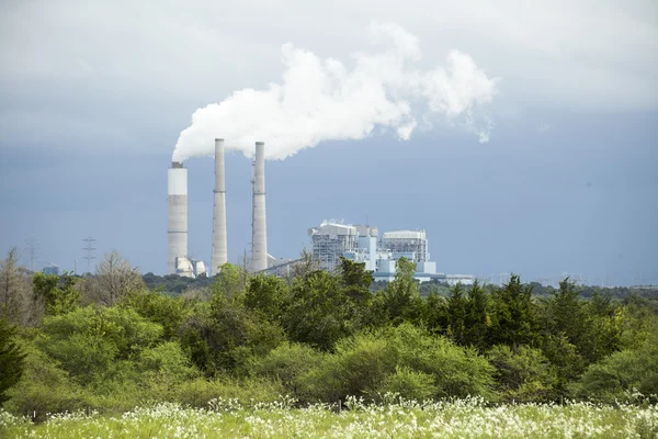 La vapeur monte d'une usine au loin . Images De Stock Libres De Droits