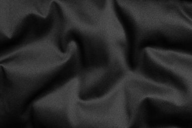 Black fabric texture with soft folds and smooth surface, close-up background.