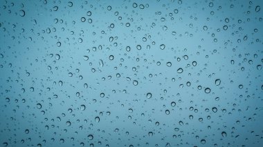 Şeffaf bir yüzeye eşit olarak yayılmış yağmur damlaları, gökyüzü mavisi arka planda, her damla ışığı yakalar ve doğal desenler oluşturur. Tazelik ve yağmurlu gün sadeliği kavramı
