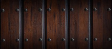 Dikey olarak sıralanmış görünen metal perçinlerle koyu ahşap paneller, çeşitli tasarım projeleri için uygun doğal tahıl ve dokuyu vurguluyor.