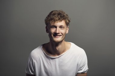 Yakışıklı duygusal adam gri arka plan üzerinde bir stüdyoda poz bir gülümseme ile