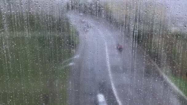 Kilátás az útra egy nedves ablakon keresztül cseppekkel, az eső alatt az emberek tükörképével — Stock videók