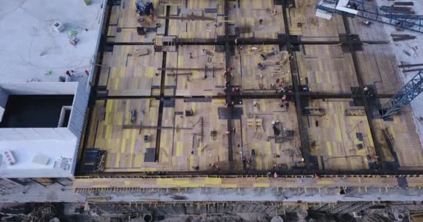 Construcción de un edificio con grúa en el tejado con trabajadores y materiales — Vídeo de stock