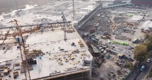 Dron przelatujący nad placem budowy centrum handlowego ze sprzętem budowlanym i pracownikami — Wideo stockowe