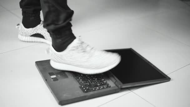 Programista skacze ze stopami w gniewie na starym laptopie, który pracował powoli, czarno-biały film — Wideo stockowe