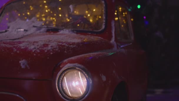 Червоний сніговий рідкісний автомобіль зі святковим новорічним освітленням . — стокове відео