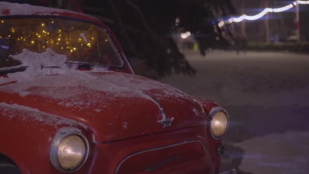 Red snow-covered rarity car with festive New Year illumination. — Stock Video