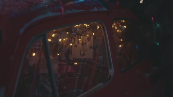 Červená zasněžená rarita auto s slavnostní novoroční osvětlení. — Stock video