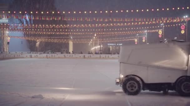 Ice recovery and maintenance machine on a skating rink, evening, colored lights, snowfall. Ukraine, Kiev January 14, 2021 — Stock Video