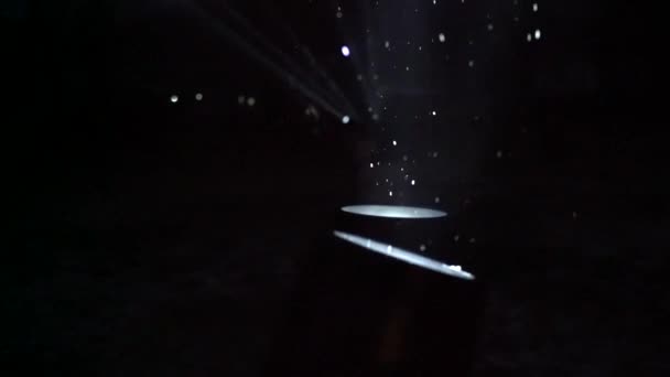 Концертные прожекторы ночью во время снегопада, снежинки, вращающиеся на свет — стоковое видео