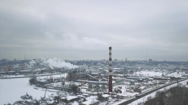 Endüstriyel bölgeden ısı güç şebekesinin borusuna uçun. Buz içinde donmuş suyla dolu bir yükleme rıhtımı olsun. Şehrin arka planında duman bulutları. — Stok video