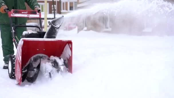 Febrero 13, 2021 Kiev Ucrania, Trabajador con mono verde elimina la nieve con una máquina de arado de nieve MTD rojo — Vídeos de Stock