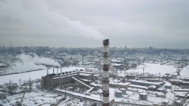 Volo sopra la zona industriale al tubo della rete elettrica termica con una banchina di carico con acqua ghiacciata nel ghiaccio. Piume di fumo sullo sfondo della città. — Video Stock