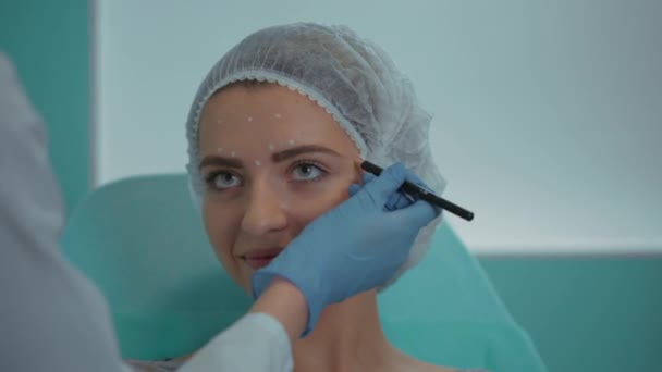 O esteticista no escritório marca o rosto dos clientes com um lápis de close-up — Vídeo de Stock