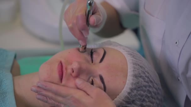 Kosmetologischer Eingriff Mikrodermabrasion bei einem Mädchen mit Problemhaut. Die Kosmetikerin macht dem Patienten einen Behandlungsvorgang. — Stockvideo