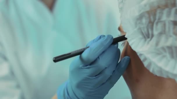 Die Kosmetikerin im Büro markiert das Gesicht der Kunden mit einem Bleistift in Großaufnahme — Stockvideo