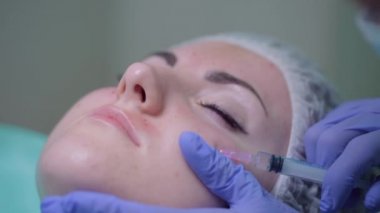 Güzellik uzmanı hastaya bir tedavi prosedürü uygular. Bir güzellik uzmanı bir kadının yüzüne iğne yapar. Mezoterapi. Tıbbi eldivenli doktor enjeksiyonlu