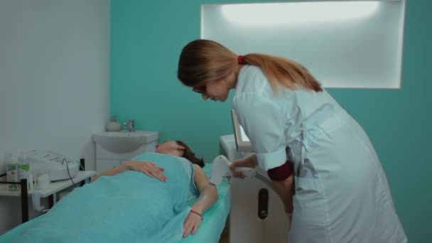 여성의 다리에 레이저 머리카락 제거. 그 소녀는 진료실의 소파에 누워 있다. 미용사의 손 이 그 다리를 소독 한다. — 비디오