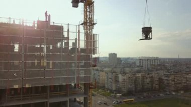 Yüksek bir binanın çatısında betonla dolu bir sarnıç dikmek inşaat halindeki işçilerle şehir hayatının arka planında, arka planında