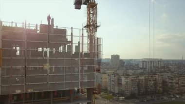 Yüksek bir binanın çatısında betonla dolu bir sarnıç dikmek inşaat halindeki işçilerle şehir hayatının arka planında, arka planında
