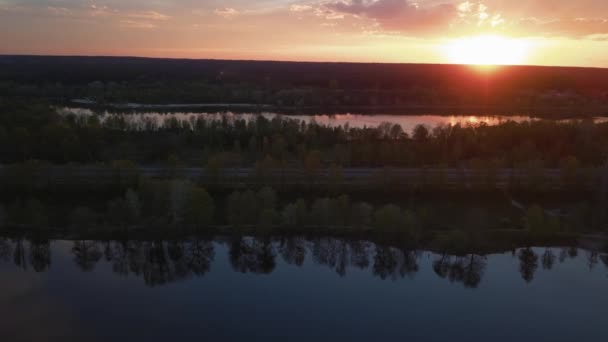 Kleurrijke zonsondergang over de weg met auto 's met uitzicht op het bos en het meer Oekraïne, Kiev op 6 mei 2021. — Stockvideo