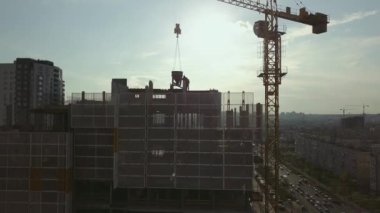 İnşaat halindeki bir bina boyunca kamerayı kaldırıp çatıdaki işçilere ve boş zıt güneş ışığına bakmak.