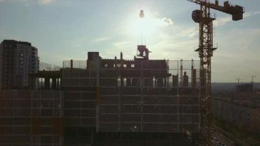 İnşaat halindeki bir bina boyunca kamerayı kaldırıp çatıdaki işçilere ve boş zıt güneş ışığına bakmak.
