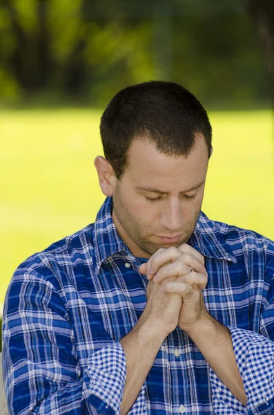 Mann betet in einem Park. Stockbild