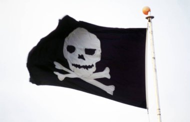 Tamamen parçalanmış ve ezilmiş siyah korsan bayrağı (Jolly Roger) rüzgarda bir boynuz flüte sarılmış yama ve kumaşın üzerine çizilmiş beyaz arka planda iki kılıç ile kafatası ile