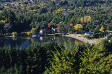 Sonbaharda ağaçlı orman ve soğuk bir sabah pintoresk neuquen arjantin panoramik viux akçaağaç lacar gölü lüks evi yapraklarının arasından güneş.