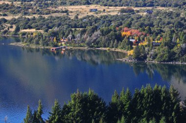 Sonbaharda ağaçlı orman ve soğuk bir sabah pintoresk neuquen arjantin panoramik viux akçaağaç lacar gölü lüks evi yapraklarının arasından güneş.
