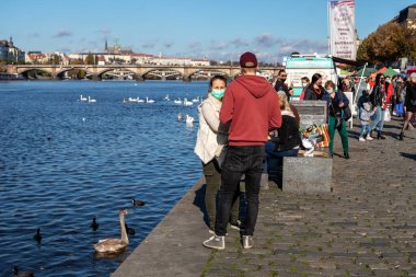 PRAG, CZECH REPUBLIC - 24 Ekim 2020: Suratlı insanlar Coronavirus salgınının ikinci dalgası sırasında Naplavka çiftçi pazarında kuğuları besleyen maskeler