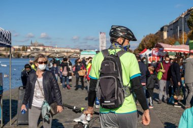 PRAG, CZECH REPUBLIC - 24 Ekim 2020: Coronavirus salgınının ikinci dalgası sırasında Naplavka çiftçi pazarında yüz maskeli bisikletçi