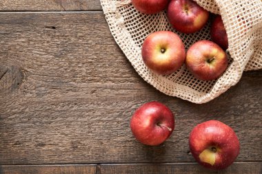 Organik pamuktan yapılmış, ekolojik olarak yeniden kullanılabilir bir ağ torbasında taze kırmızı elmalar.