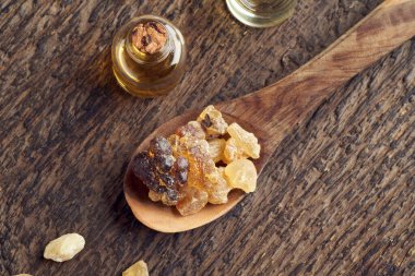 Tütsü reçinesi bir kaşıkta kristaller ve arka planda gerekli yağ şişeleri, üst görünüm