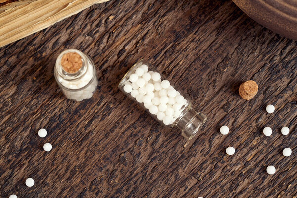Бутылка гомеопатических таблеток, пролитая на деревянном фоне