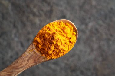 Zerdeçal tozu ahşap bir kaşık üzerinde gri bir arkaplan üzerinde, üst manzara