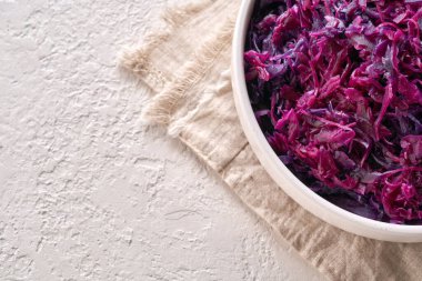 Fotokopi alanı ve üst görünümü olan beyaz arka planda bir kasede mayalanmış mor lahana.